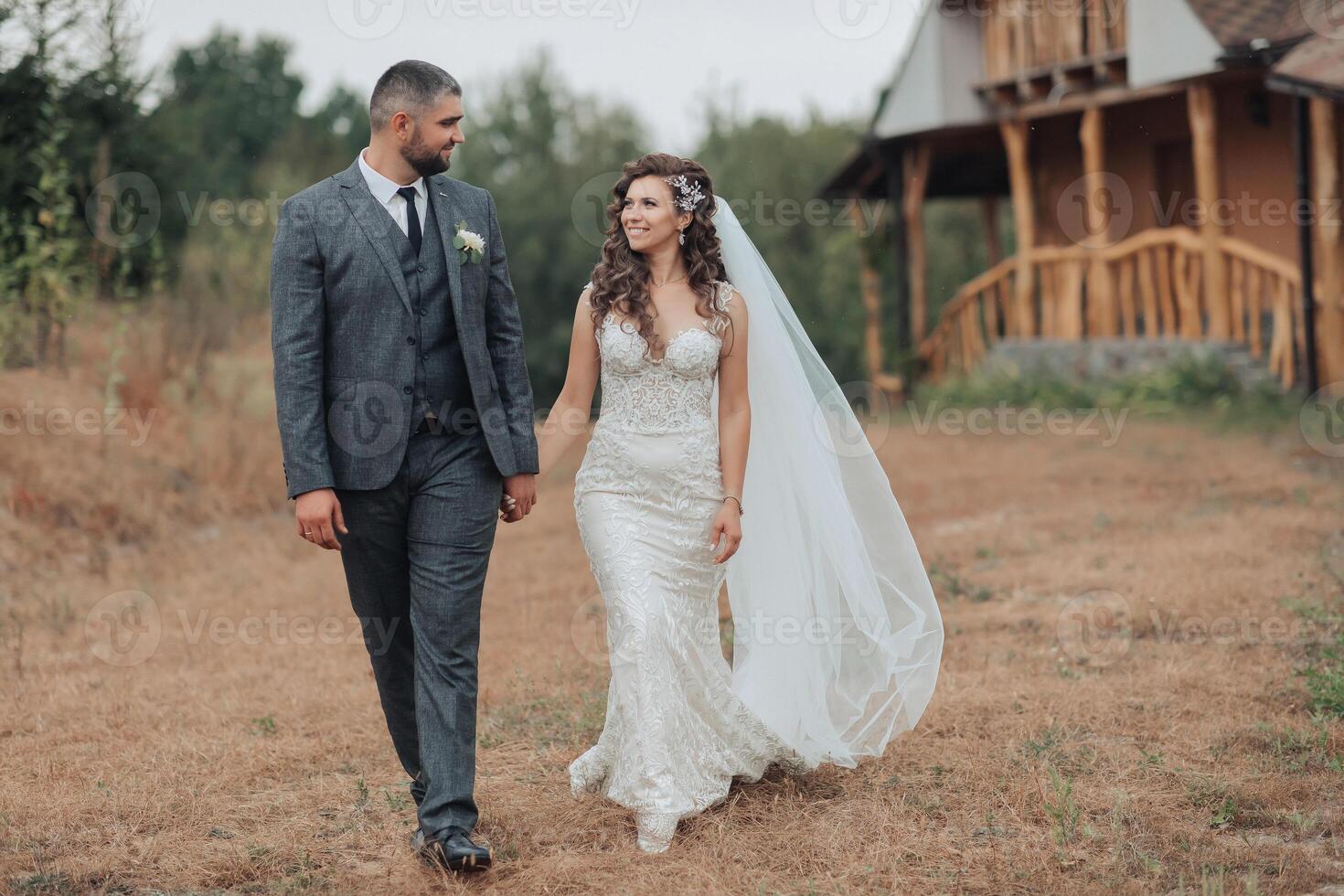 A bride and groom are walking together in a field photo