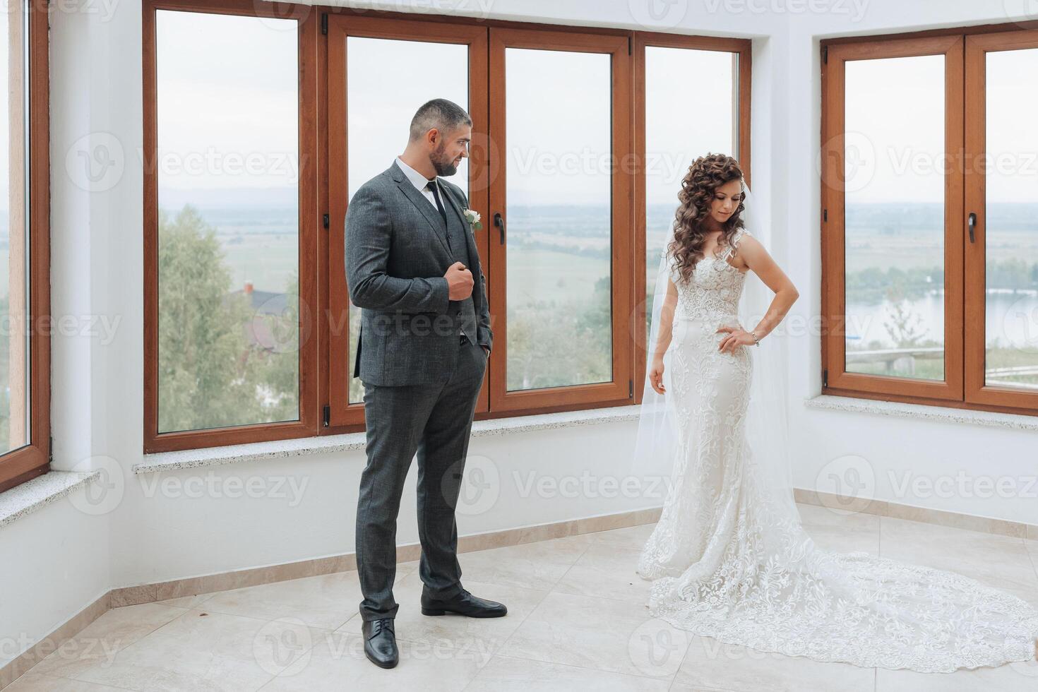 A man and a woman are standing in front of a window, the man is wearing a suit photo