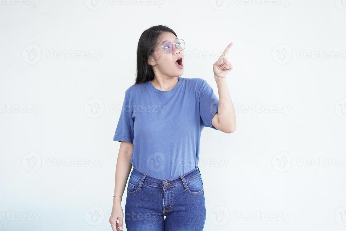 Beautiful Asian woman looks shocked, with a 'wow' expression, pointing to the side with her forefinger photo