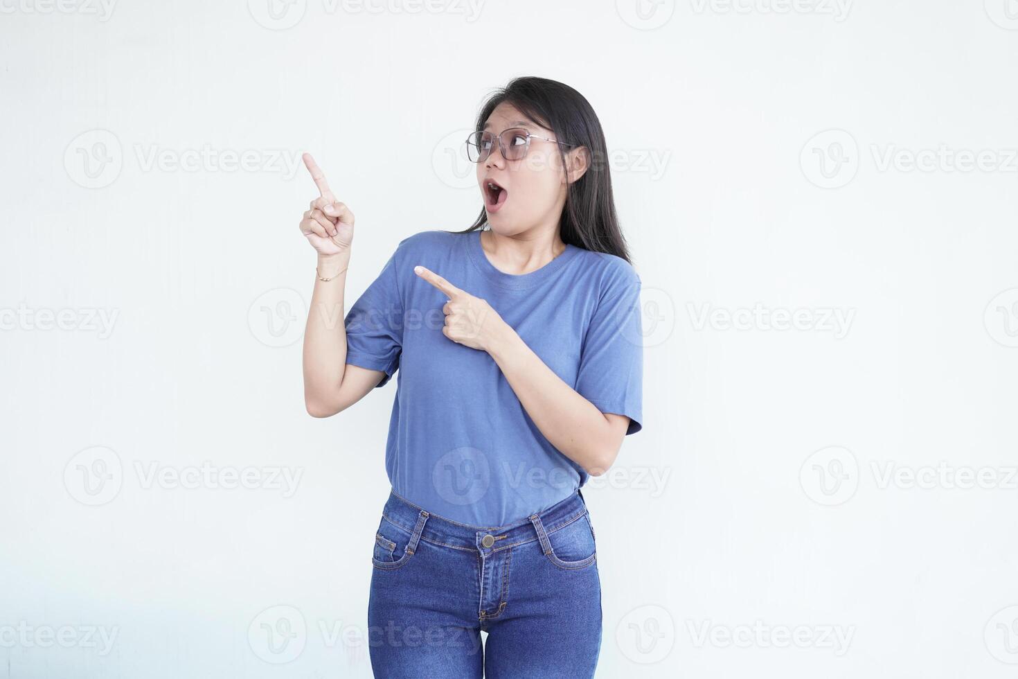 Beautiful Asian woman looks shocked, with a 'wow' expression, pointing to the side with her forefinger photo