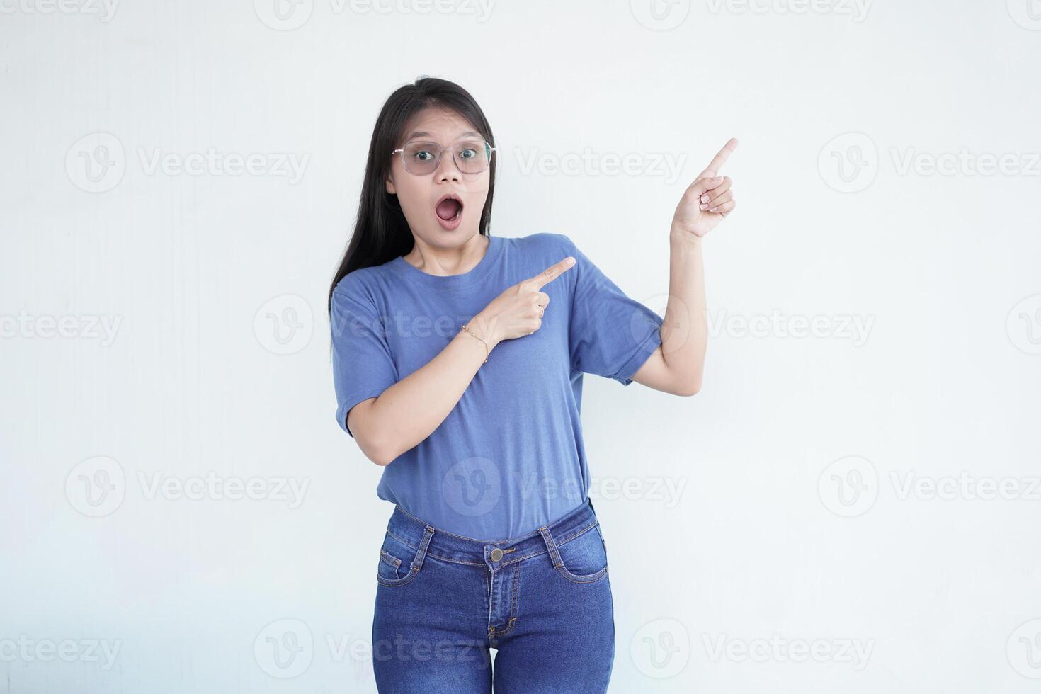 Beautiful Asian woman looks shocked, with a 'wow' expression, pointing to the side with her forefinger photo