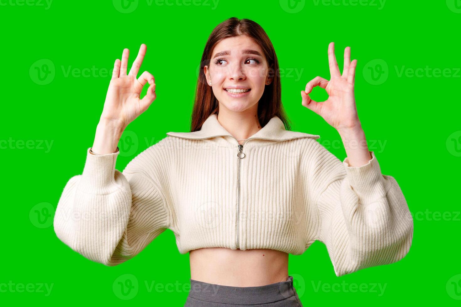A woman dressed in a skirt and sweater is standing and waving her hand in the air, possibly in a greeting or to get someones attention. photo