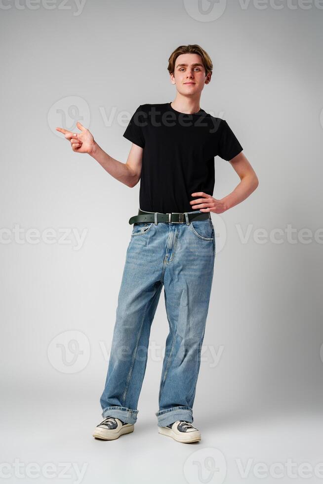 Young Man in Black T-Shirt Gesturing With Hand Against a Gray Background photo