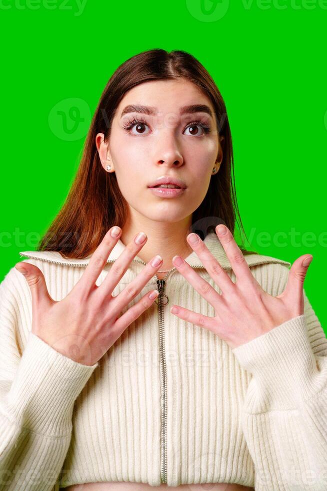 Young Woman With a Surprised Expression Standing Against a Green Background in Daylight photo