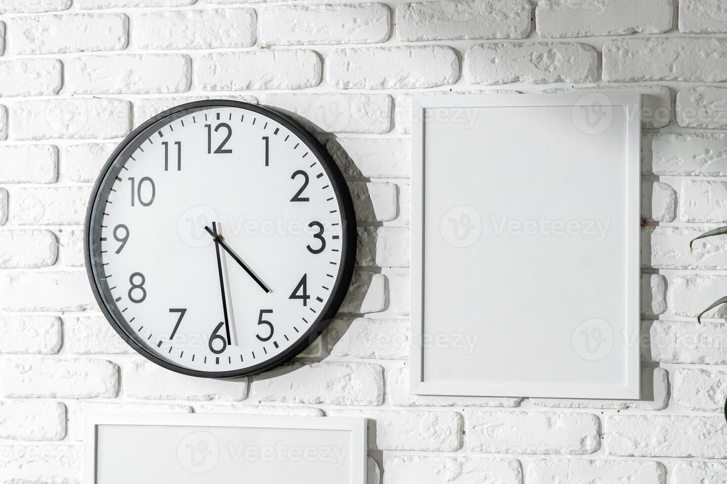 Minimalist White Wall Decor Featuring a Clock and Blank Photo Frames