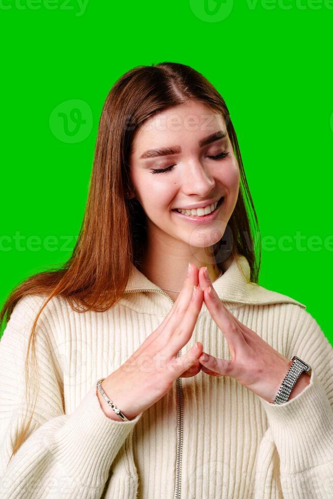 Young Woman Smiling With Closed Eyes on a Green Background Feeling Content photo