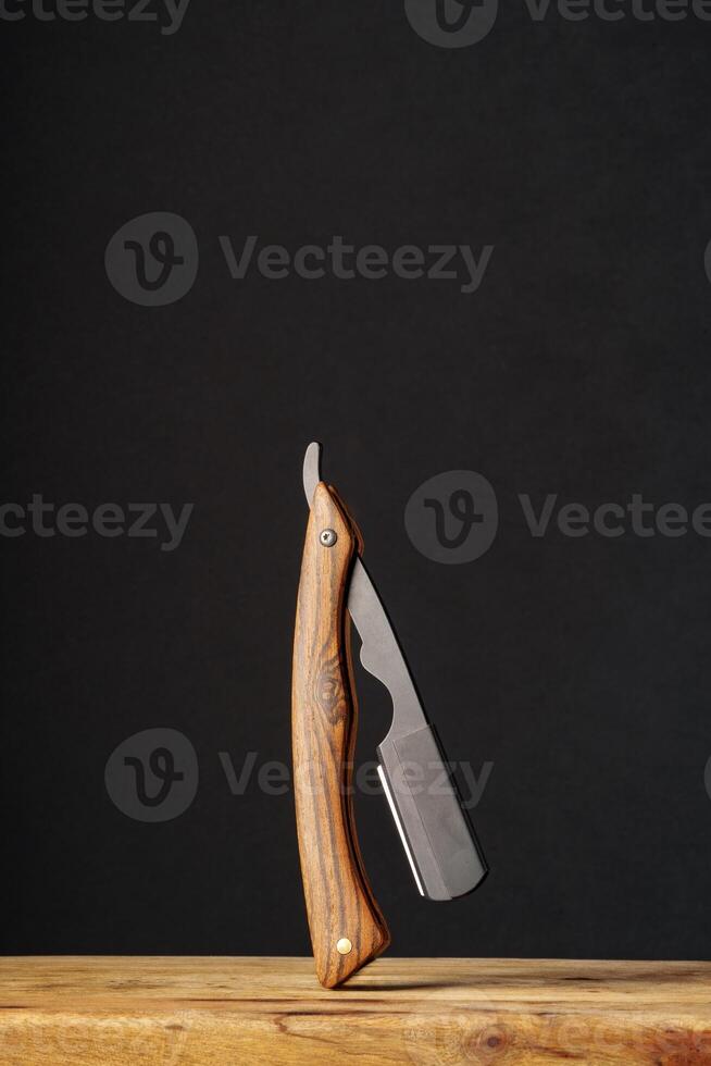 Handcrafted Wooden Folding Knife Displayed on a Rustic Table Against a Dark Background photo