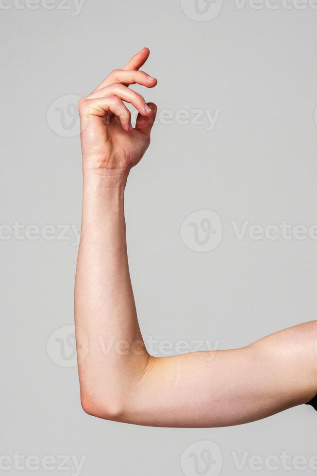 Elevated Bare Human Arm Bent at the Elbow Against a Neutral Background photo