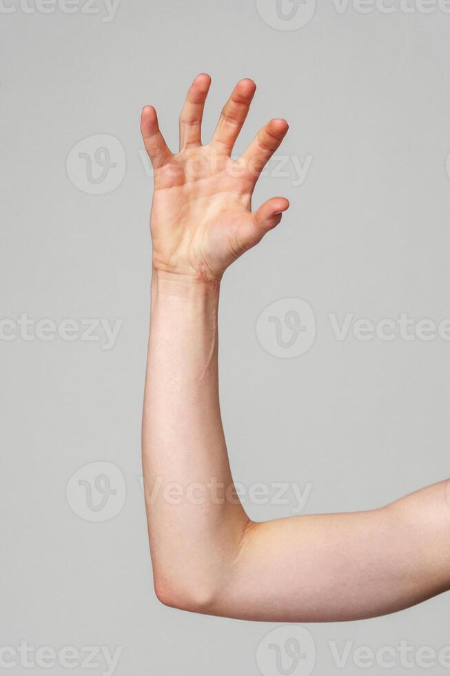 Elevated Bare Human Arm Bent at the Elbow Against a Neutral Background photo