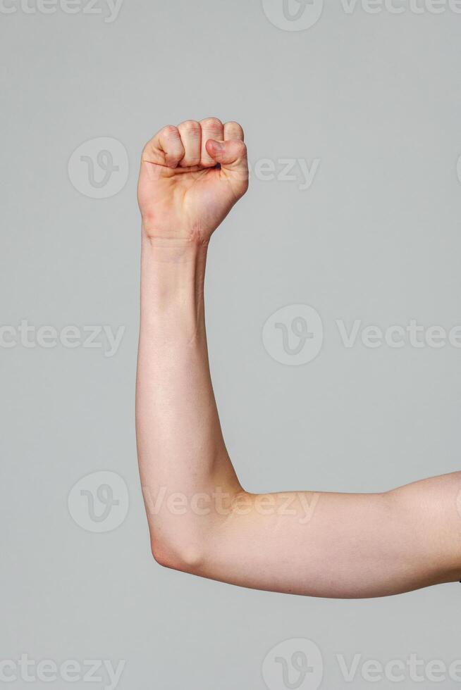 Raised Right Arm With a Clenched Fist Against a Neutral Background photo