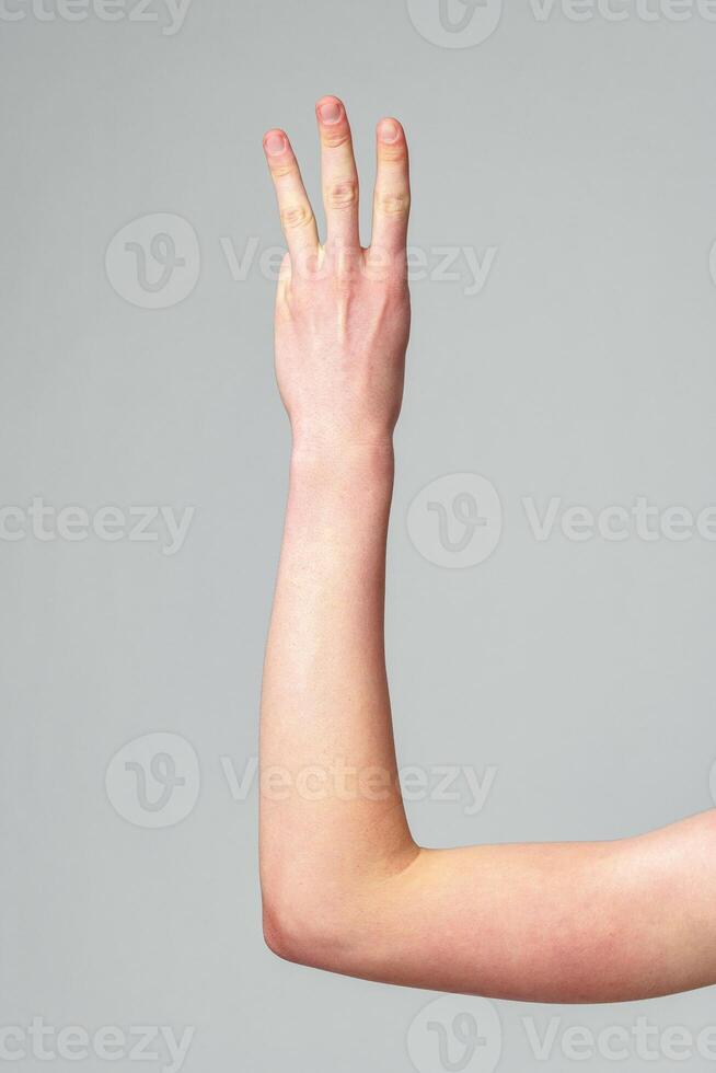Human Hand Raised in a Gesture Against a Plain Grey Background photo
