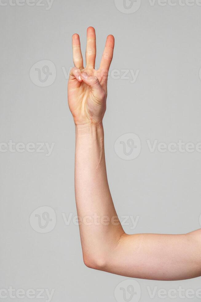 Hand Gesturing Number Three Against a Plain Background in Natural Light photo