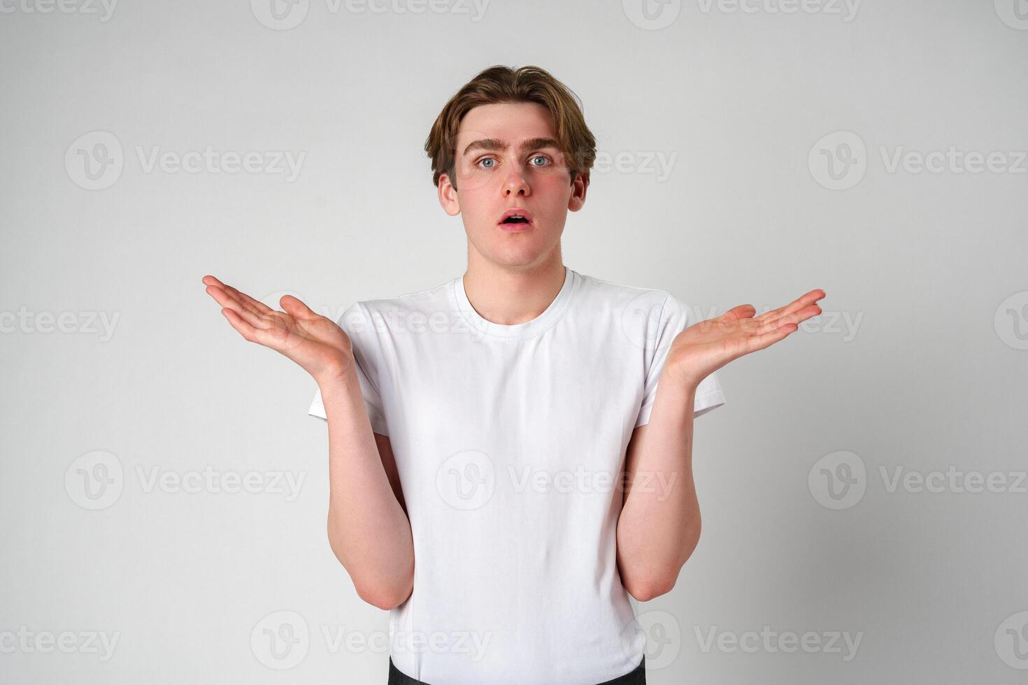 Young Man With Surprised Expression and Hands Raised in Studio Setting photo