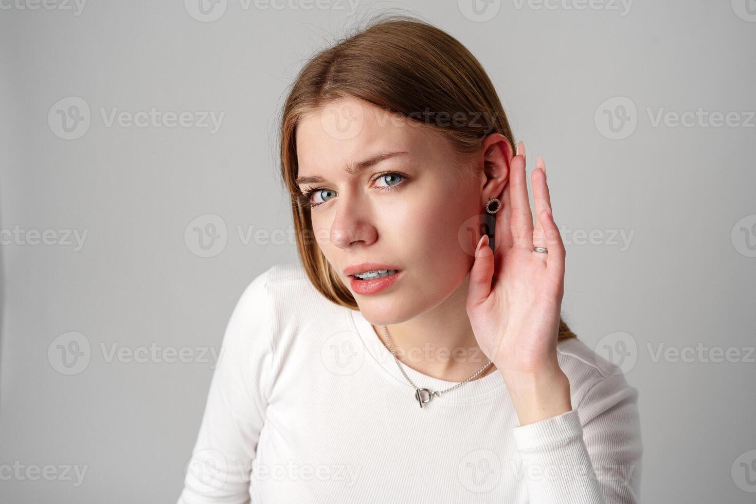 Woman Holding Hand to Ear against gray background photo