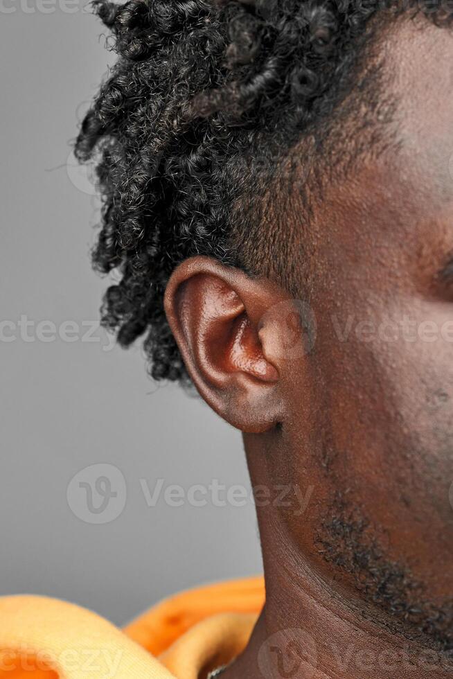 Close-Up View of African Mans Hair and Ear Against a Grey Background photo