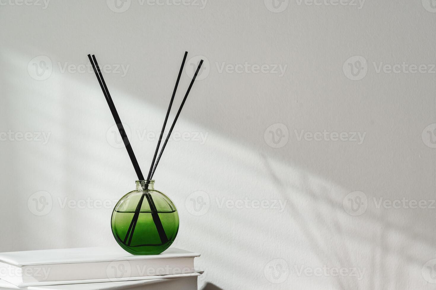 Aromatic Reed Diffuser on White Books With Shadows Playing on the Wall photo