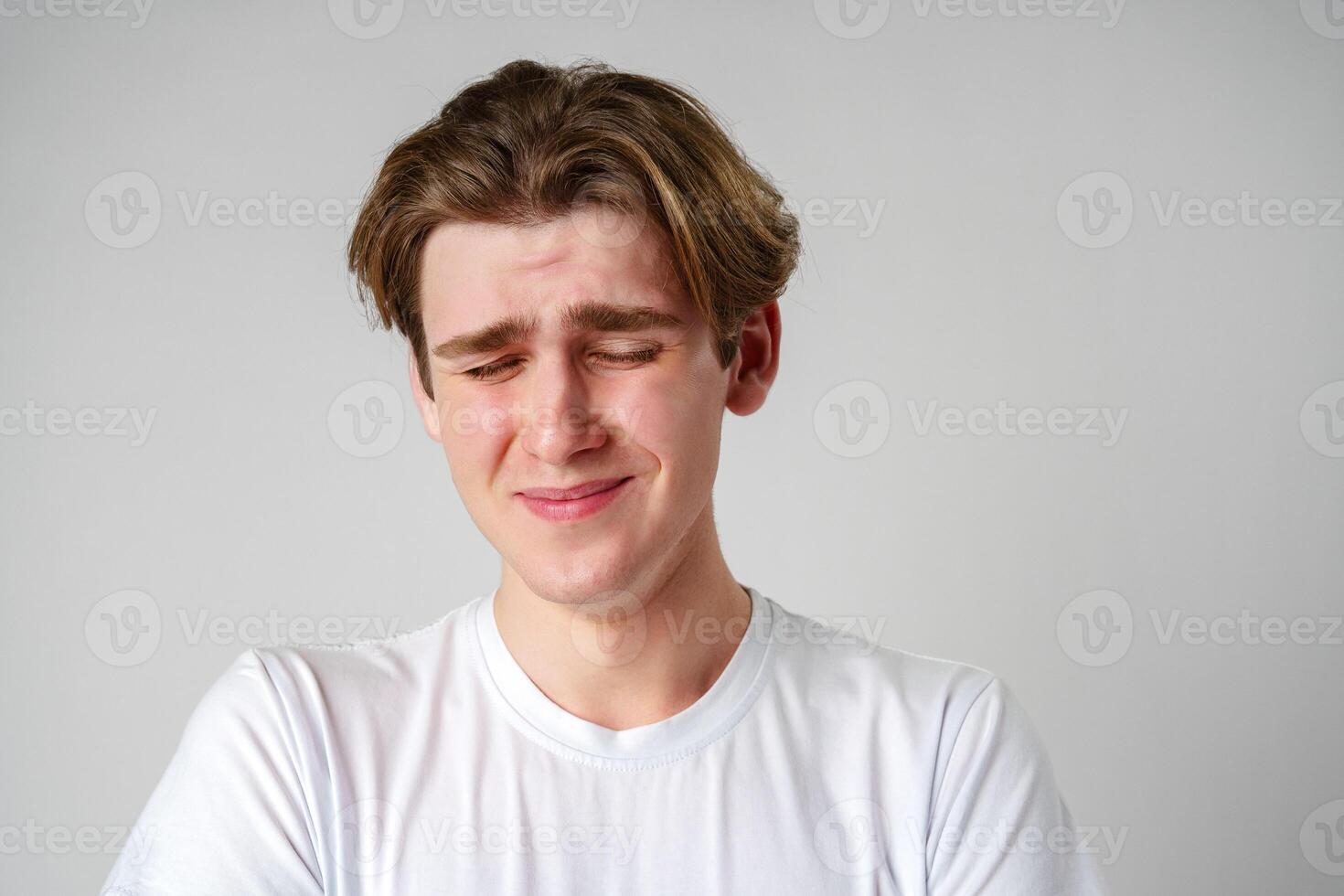 Young Man With Brown Hair Expressing Sadness Against a Plain Background photo
