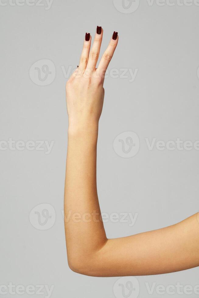 Female hand showing three fingers up on gray background photo
