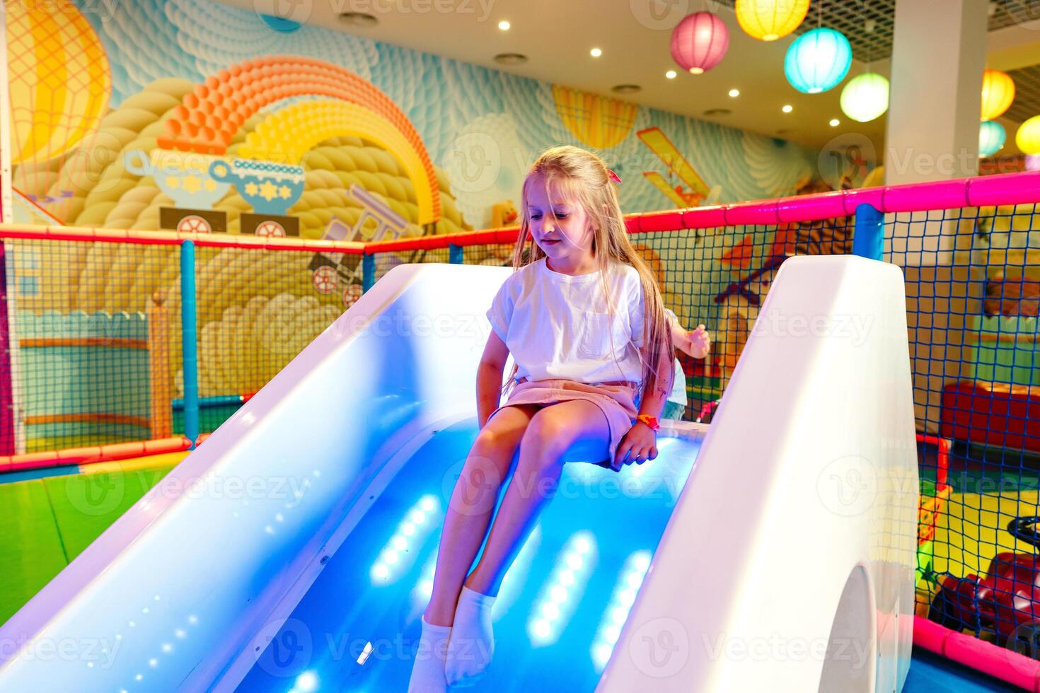 Young Girl Enjoying a Colorful Slide at an Indoor Playground photo