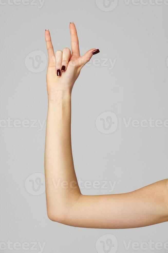 Female hand gesturing rock sign on gray background photo