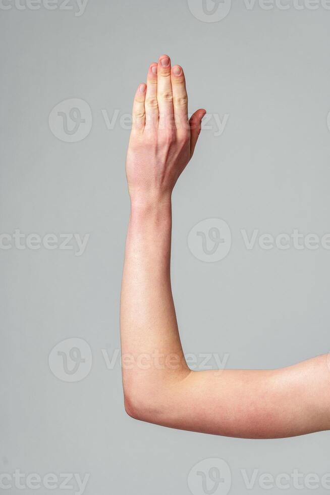Human Hand Raised Against a Neutral Gray Background in a Studio Setting photo
