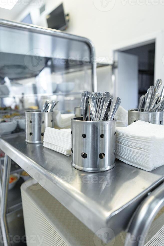 Stainless Steel Utensils Organized in Containers on a Service Cart in a Commercial Kitchen photo