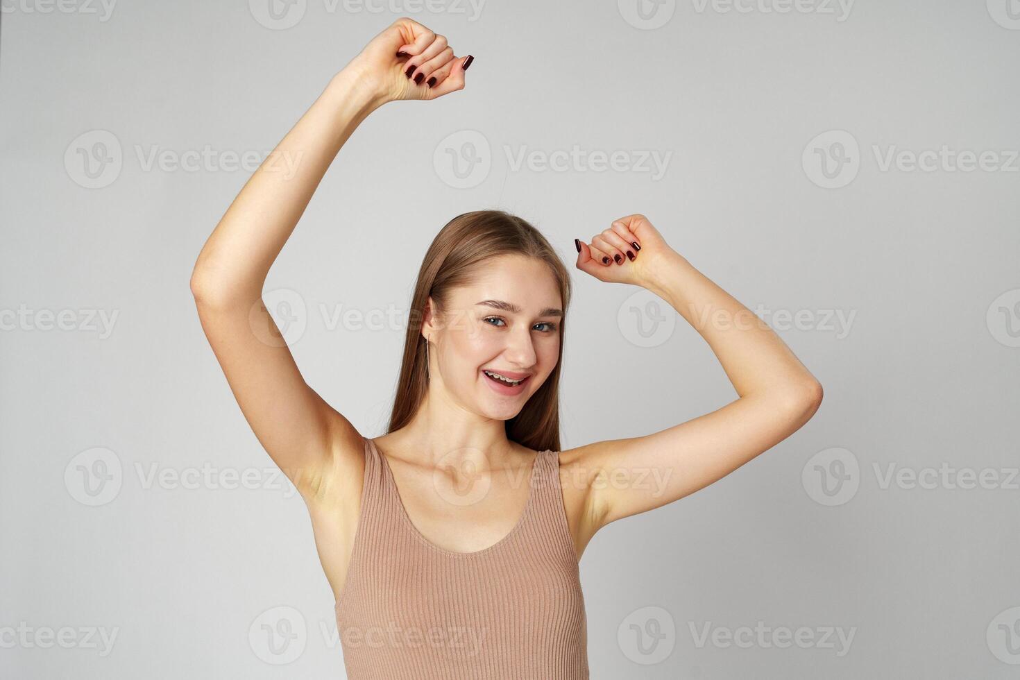 Young woman standing with her arms lifted high above her head expressing joy and triumph photo