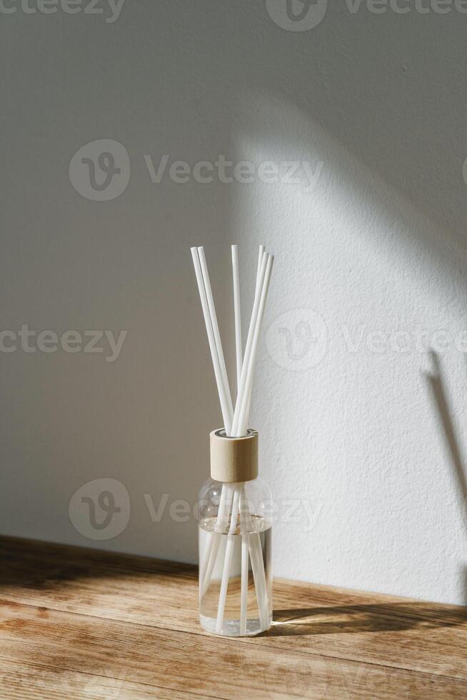 Sunlit Diffuser Bottle With Reeds Casting Shadows on a White Wall photo