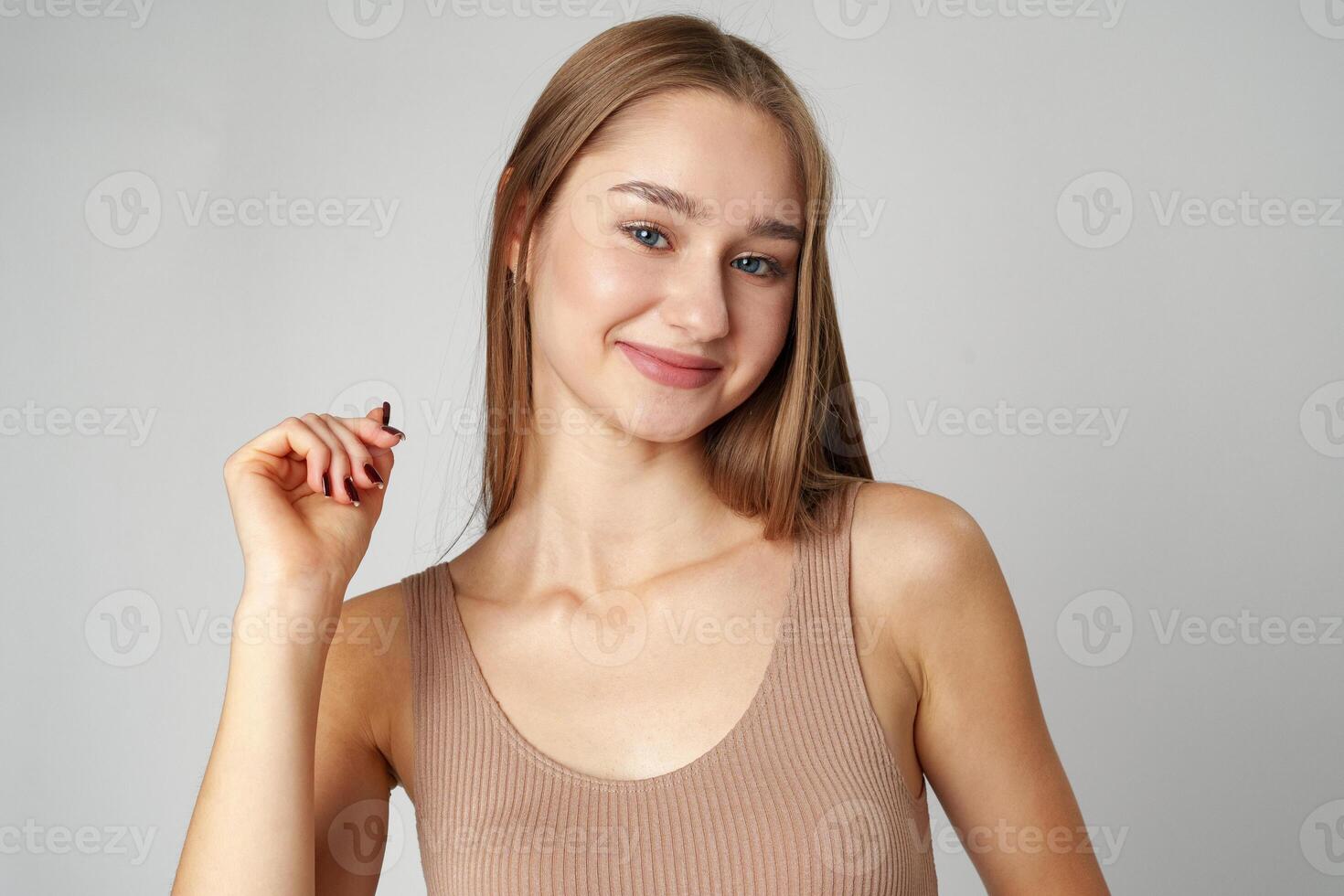 Smiling young woman posing to camera over gray background in studio photo