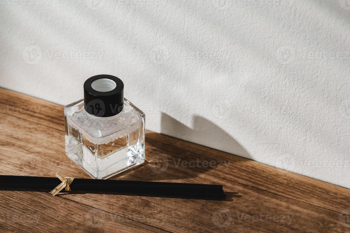 Elegant Perfume Bottle Bathed in Sunlight on a Wooden Surface photo