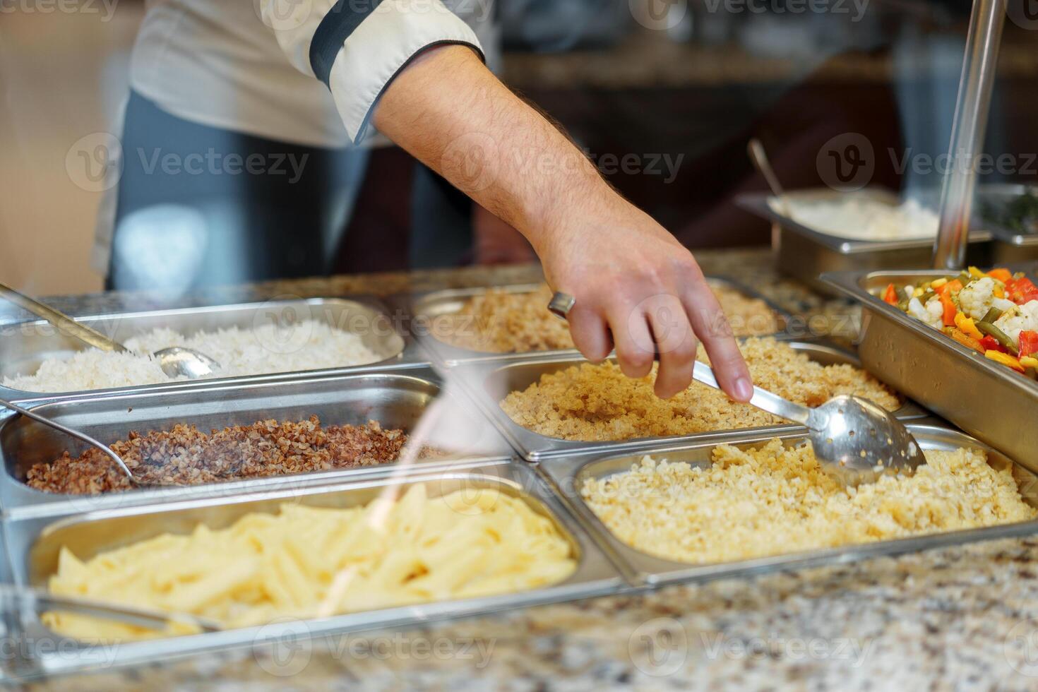 Chef Serving Freshly Cooked Dishes at a Restaurant Buffet During Lunchtime photo