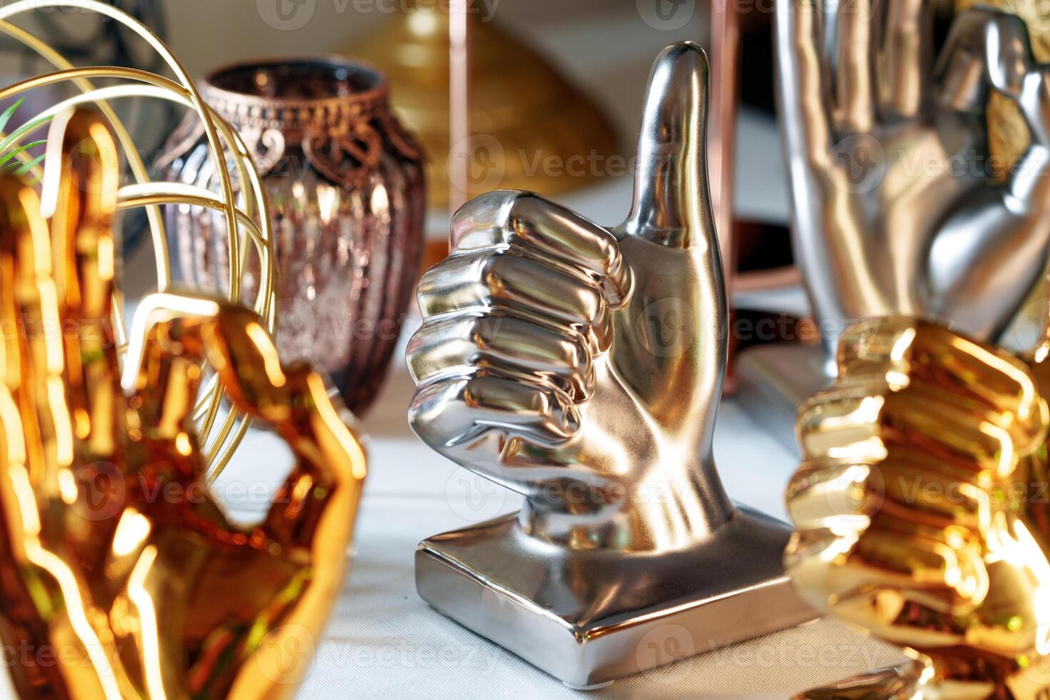 Metallic Thumbs-Up and OK Hand Gesture Sculptures Displayed on a Shelf photo