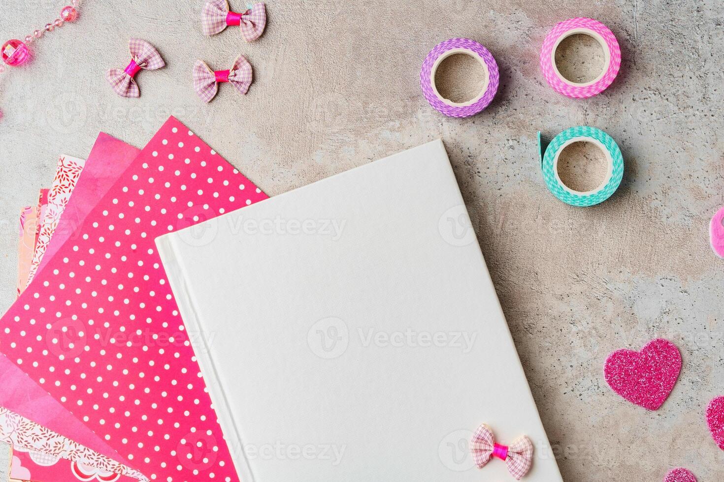 Creative supplies for scrapbooking and crafting on a textured surface with decorative tape and heart confetti photo