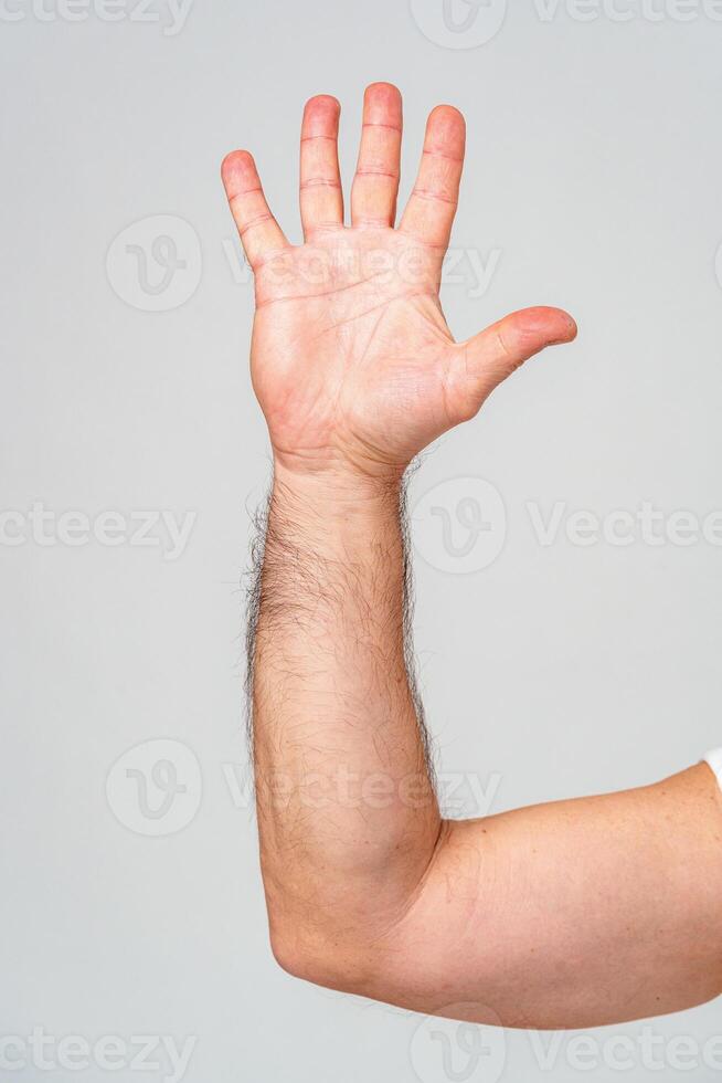 Hand raised in greeting against a plain background photo