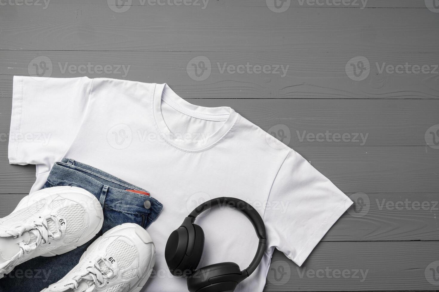 Cotton T-shirt, jeans and sneakers on wooden background top view photo