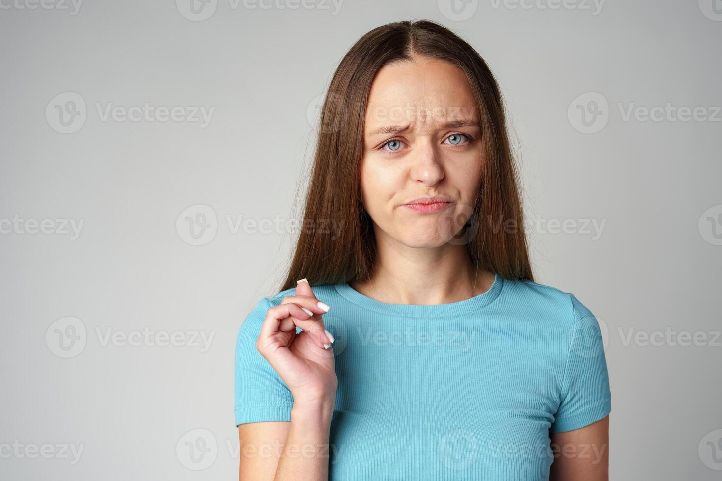Portrait of thoughtful uncertain young casual girl on gray background photo