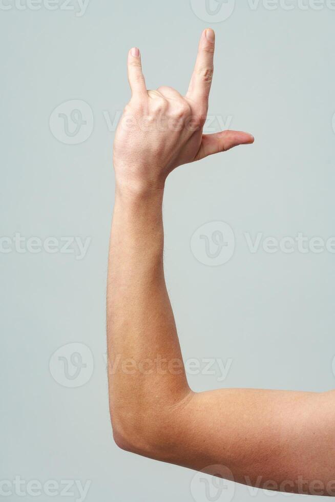 Male hand gesturing rock and roll on gray background photo