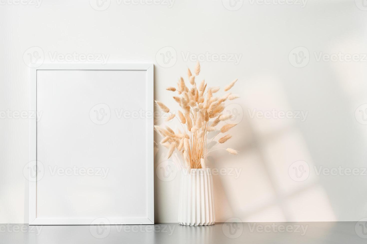 Blank picture frame and dried flower in a vase on white background photo
