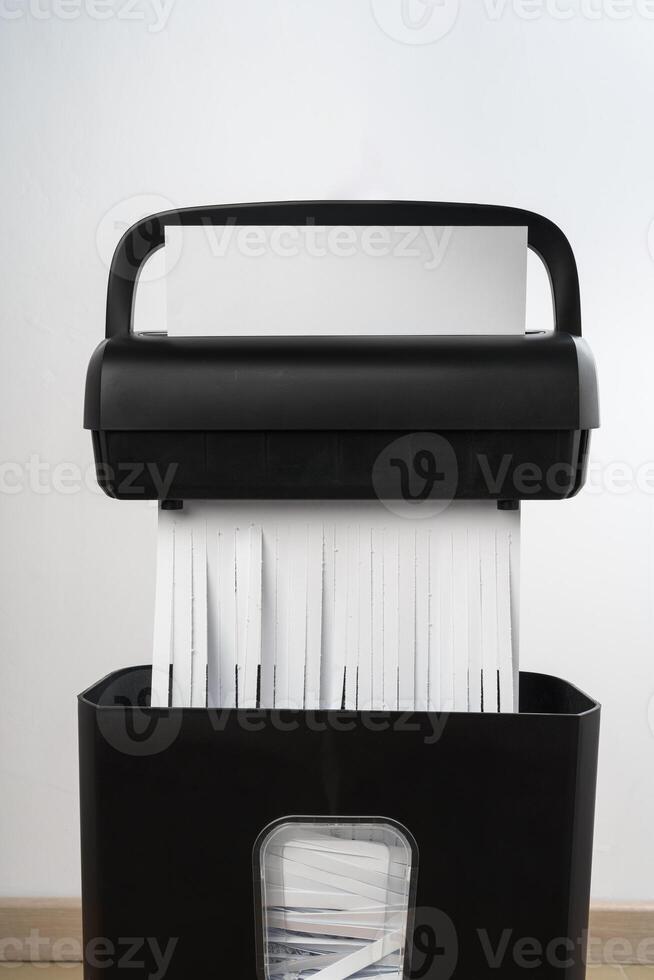 Black paper shredder cutting paper on gray background photo