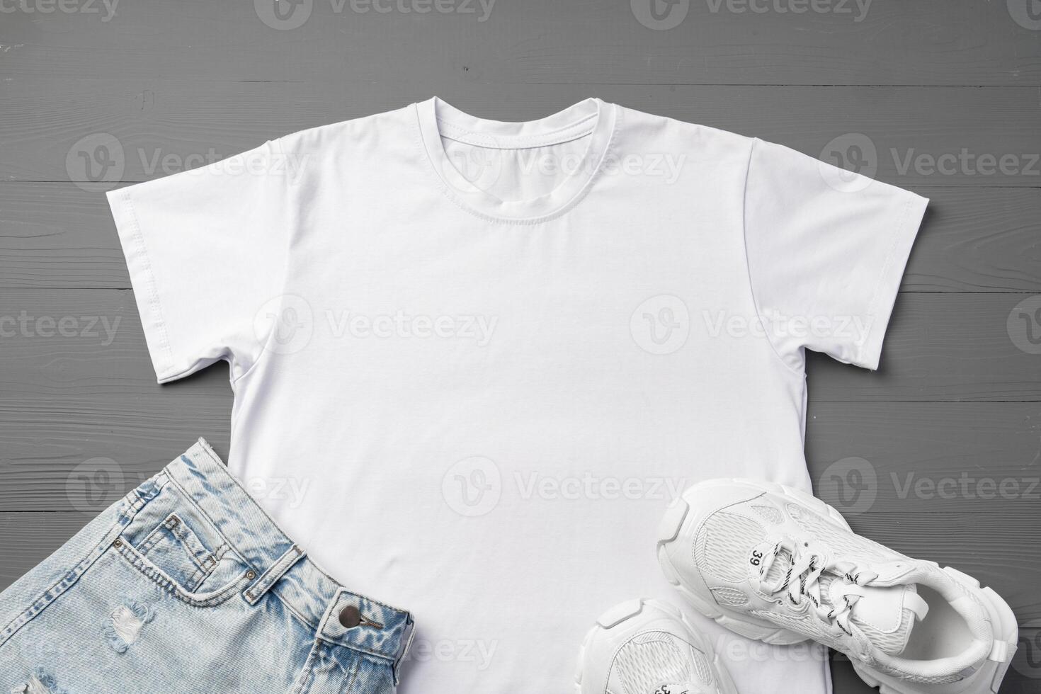 T-shirt, jeans and white sneakers on gray background top view photo