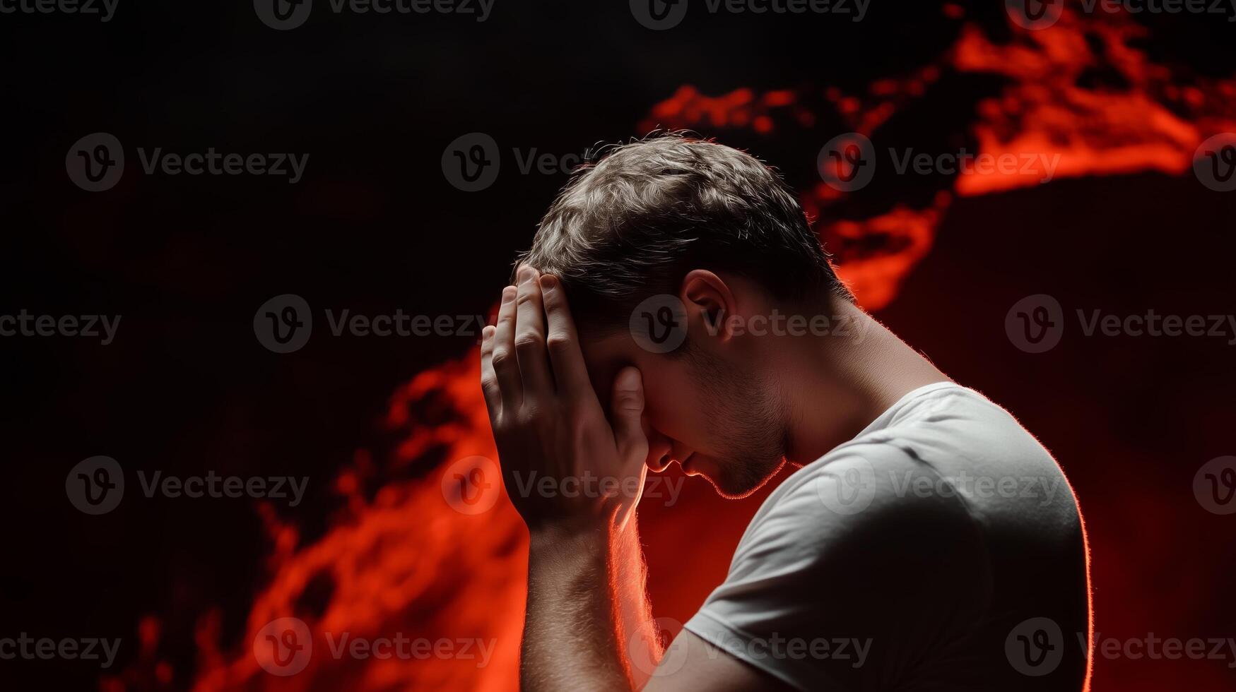 A man stands in a dramatic pose with his hands on his head, surrounded by fiery red lights creating an intense atmosphere photo