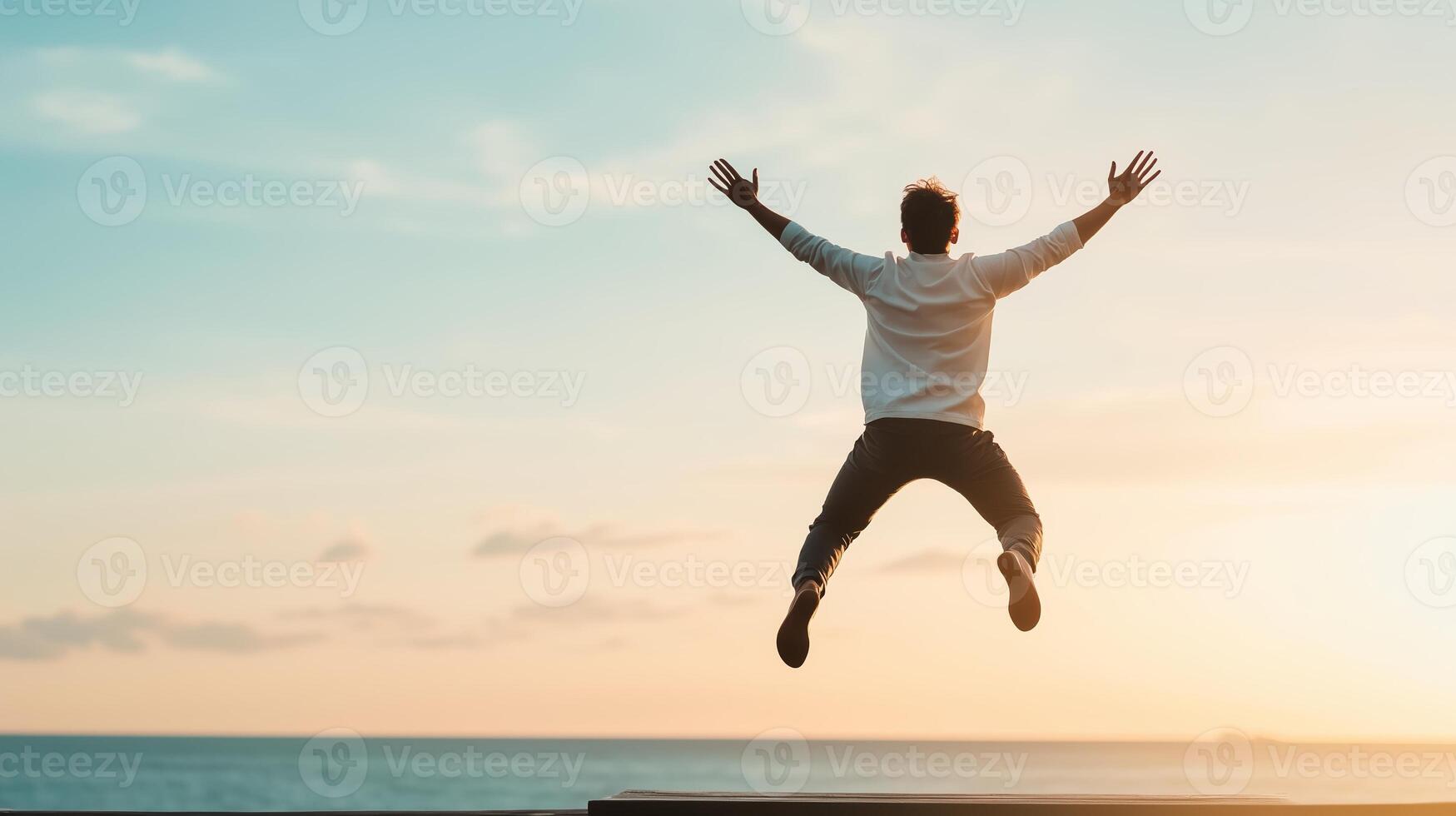 A person leaps joyfully against a sunset backdrop at the beach, capturing a moment of freedom and exhilaration just before twilight photo