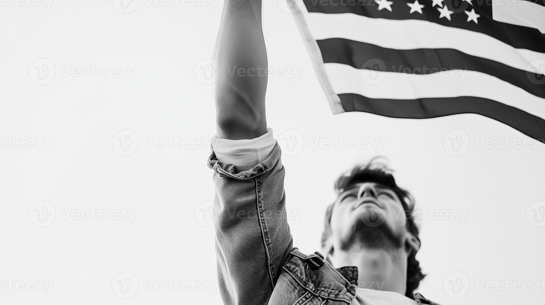 Young man proudly raising the American flag against a clear sky during a bright, sunny day photo