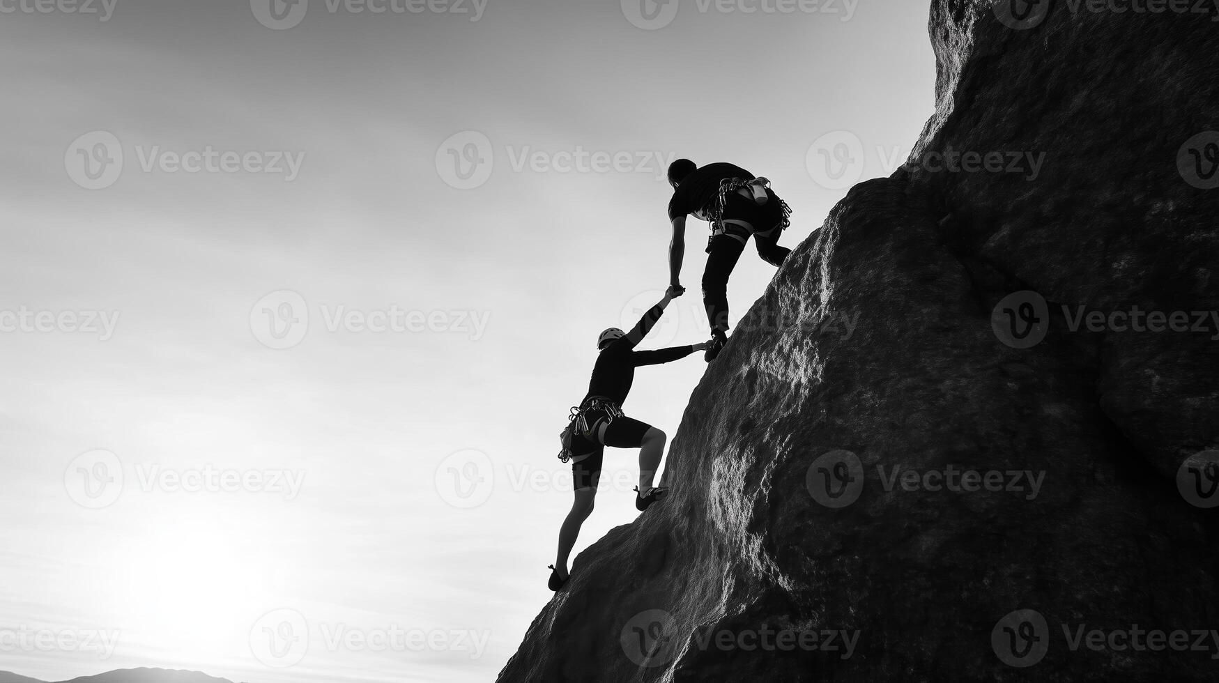 Two climbers ascending a rocky cliff during sunset, showcasing teamwork and determination in a dramatic black and white landscape photo