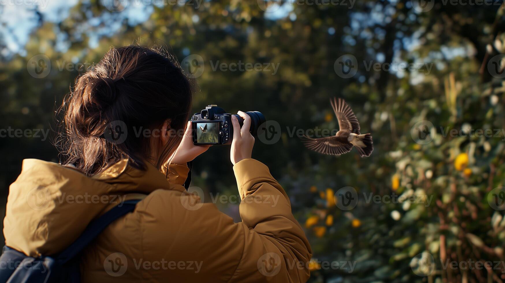 A person captures a bird in flight while exploring a vibrant nature setting with autumn foliage in a lush park during daylight photo