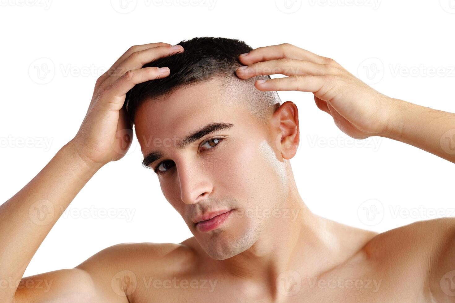 Young man standing shirtless and touching his face with hands photo