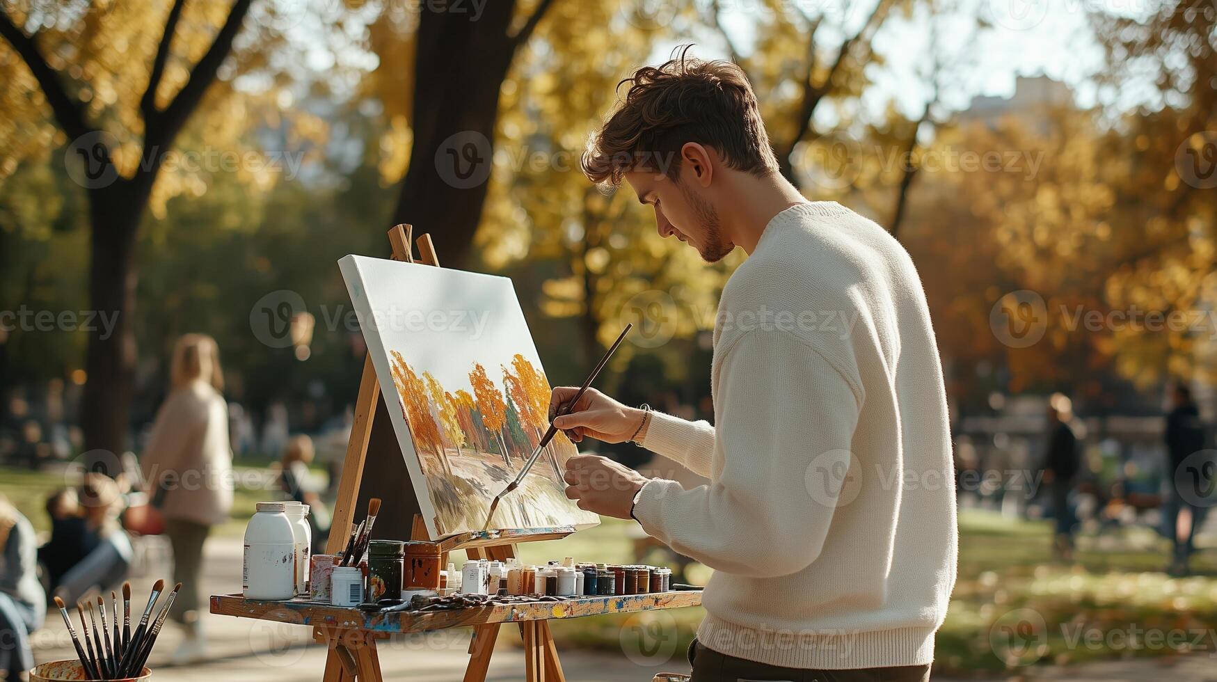 A young artist painting a vibrant autumn landscape in a public park during a sunny afternoon photo