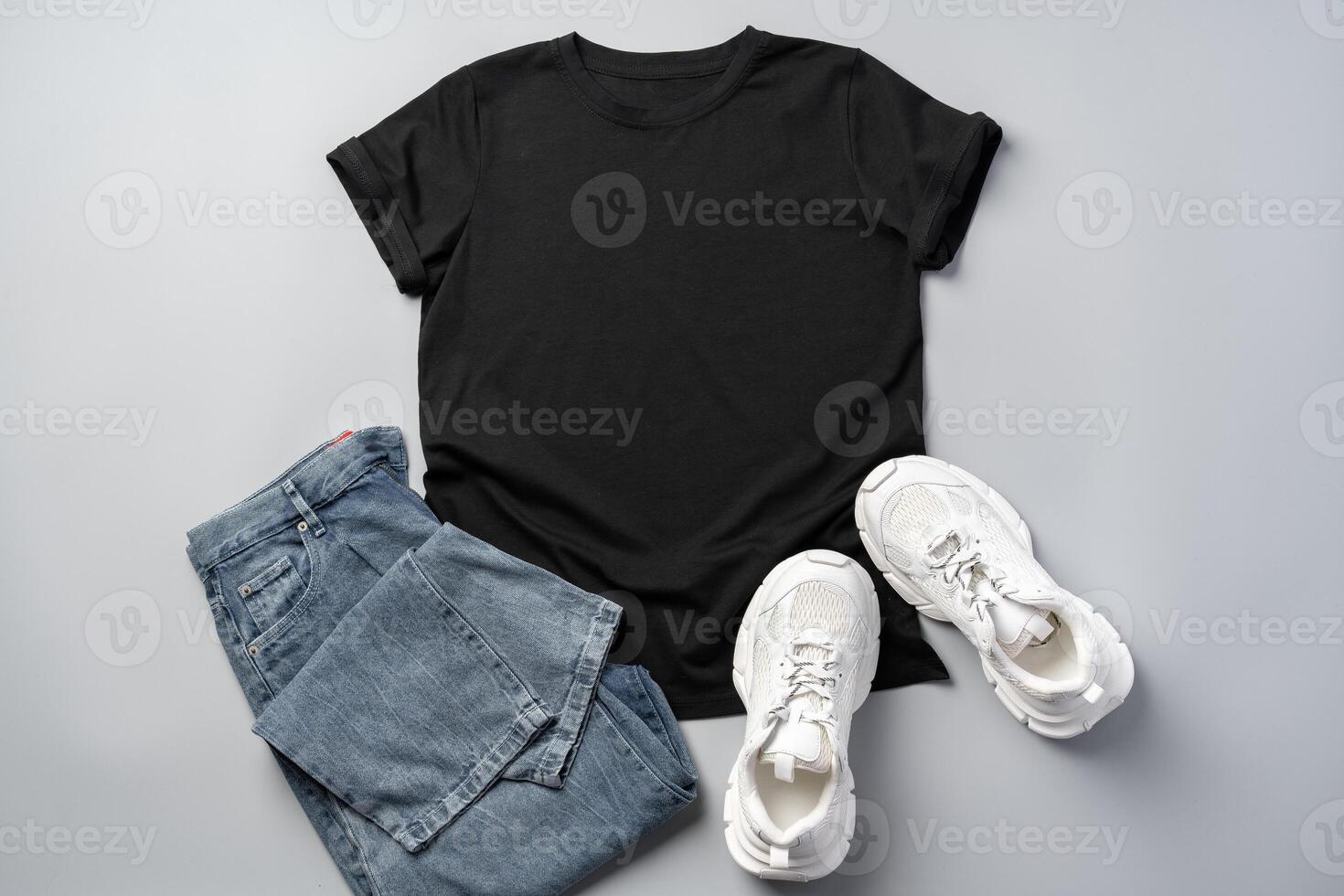 T-shirt, jeans and white sneakers on gray background top view photo