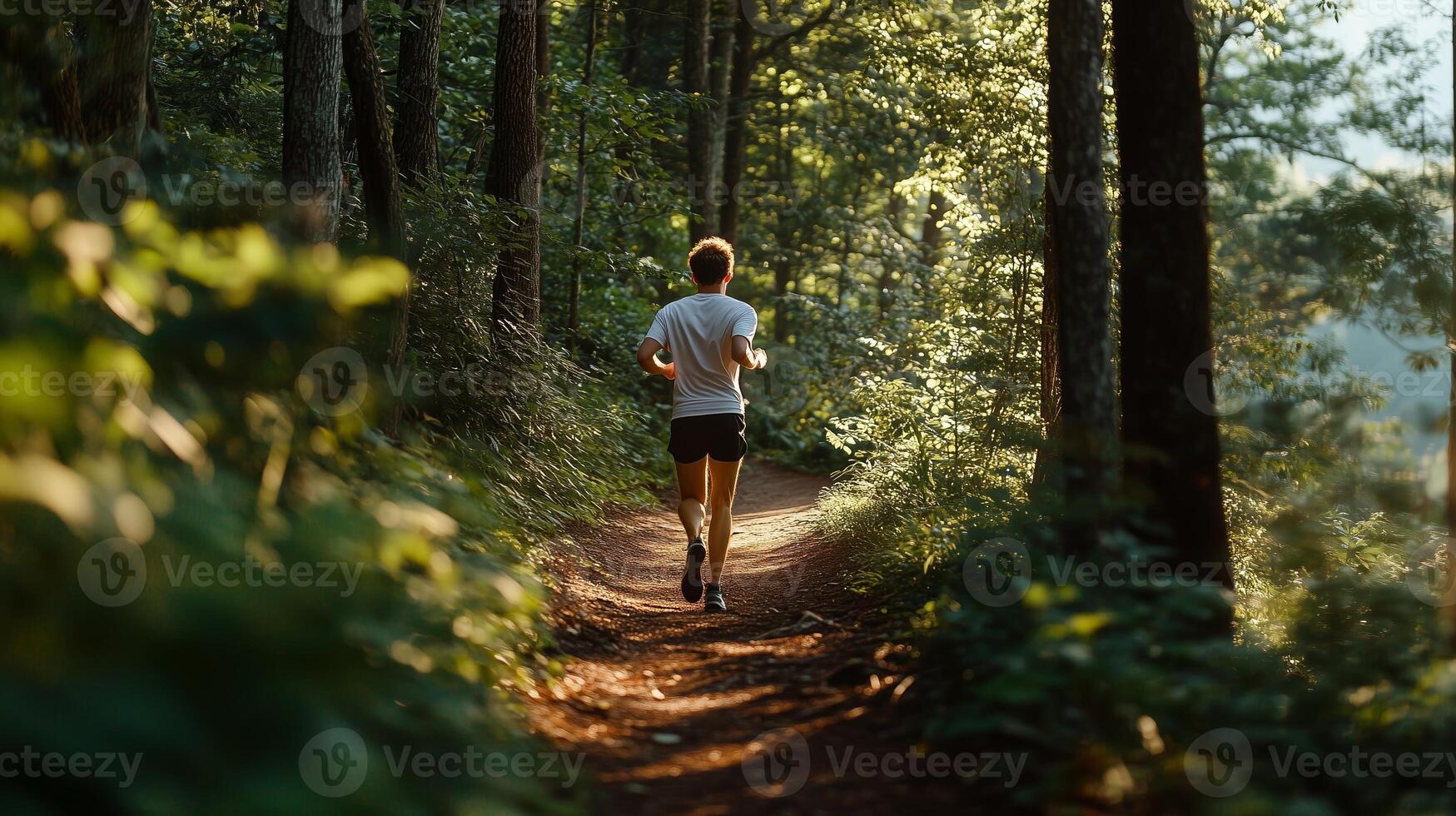 A person jogging along a sunlit forest trail surrounded by lush greenery during the early morning hours photo