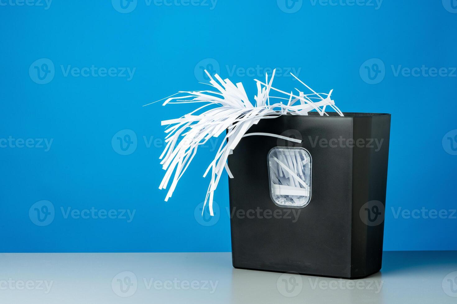 Office paper shredder on blue studio background photo